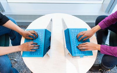 Zwei Personen arbeiten am Laptop gegenüber voneinander